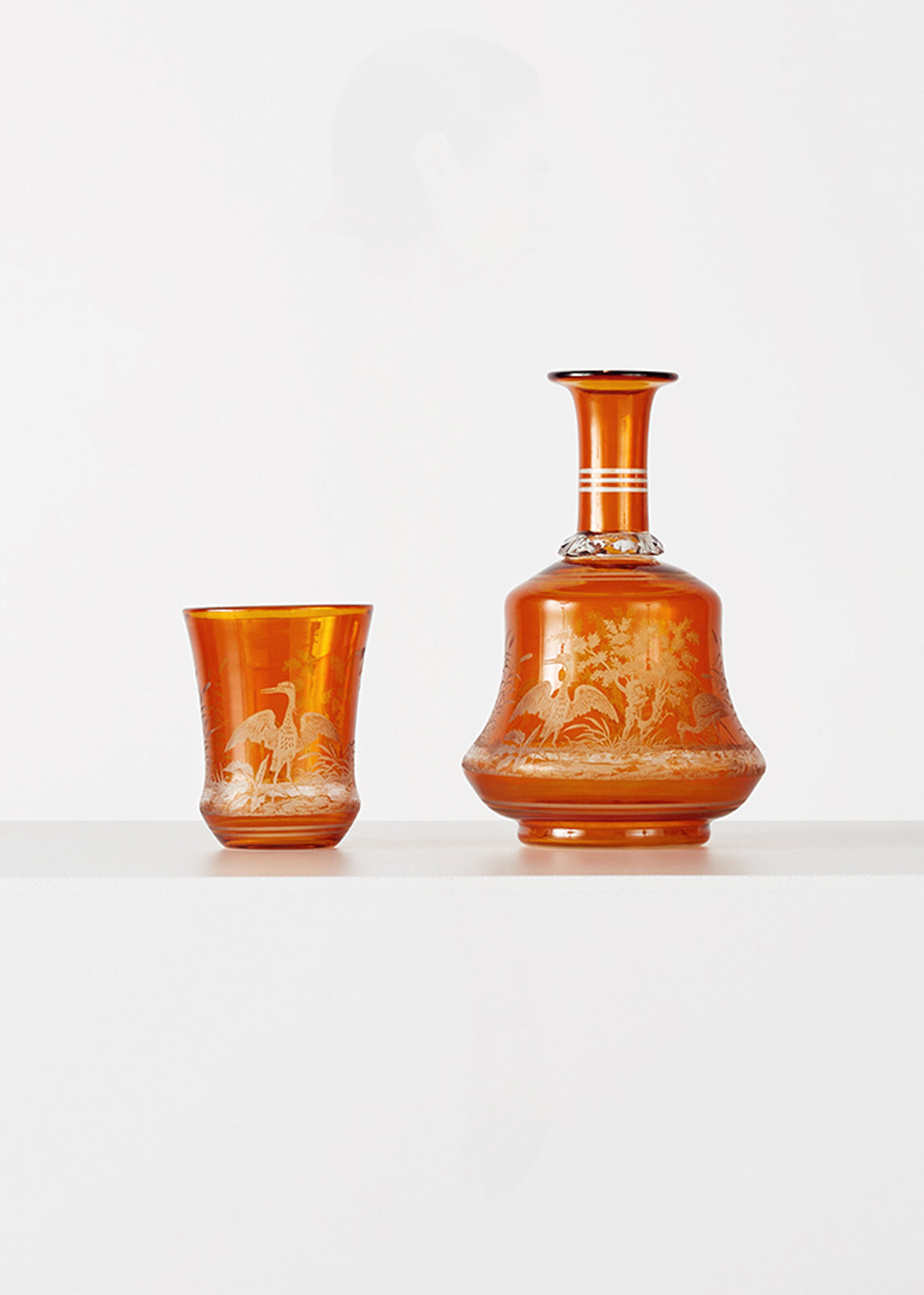 Amber colored vintaga carafe and cup, with bird and flora motif decoration